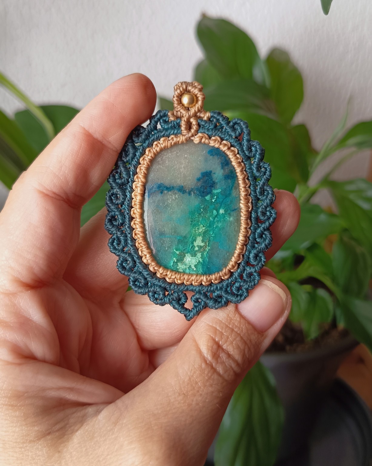 Peça oval azul-esverdeada com moldura em micro macramé azul-petróleo e nude